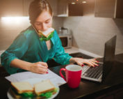 Girl with sandwhich in mouth, at computer, taking notes, Platinum Resumes, Kansas City, MO