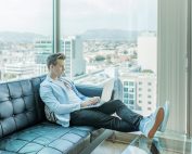 Man in highrise, on black leather couch, on laptop, Platinum Resumes, Kansas City, MO