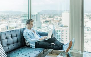 Man in highrise, on black leather couch, on laptop, Platinum Resumes, Kansas City, MO