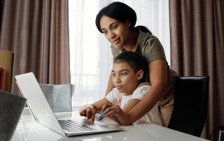 Child on laptop, mother behind helping, Platinum Resumes, Kansas City, MO