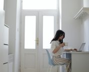 Woman in white kitchen at desk with laptop drinking coffee, Platinum Resumes, Kansas City, MO