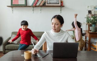 Woman working on resume at laptio with 2 kids in background, Platinum Resumes, Kansas City, MO