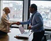 Man behind desk shaking hands with woman in a bun, Platinum Resumes, Kansas City, MO