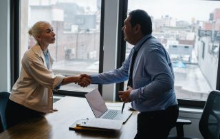 Man behind desk shaking hands with woman in a bun, Platinum Resumes, Kansas City, MO