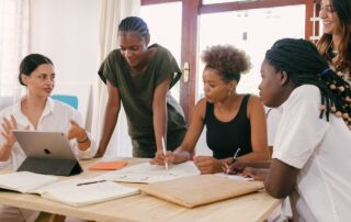 4 woman at a table writing and lokoing at a resume, Platinum Resumes, Kansas City, MO