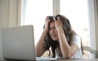 Young woman in front of her computer looking exasperated, Platinum Resumes, Kansas City, MO